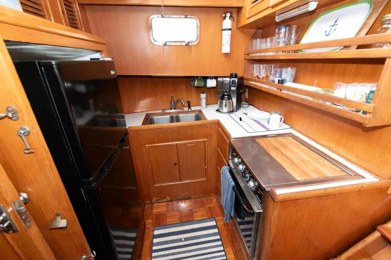 Slide: The Image of 1988 Marine Trader 48 Trawler kitchen with wood cabinetry, appliances, and striped rug. - 17