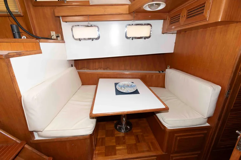 Slide: The Image of Cozy dining area in 1988 Marine Trader 48 Trawler with white seating and wooden accents. - 18