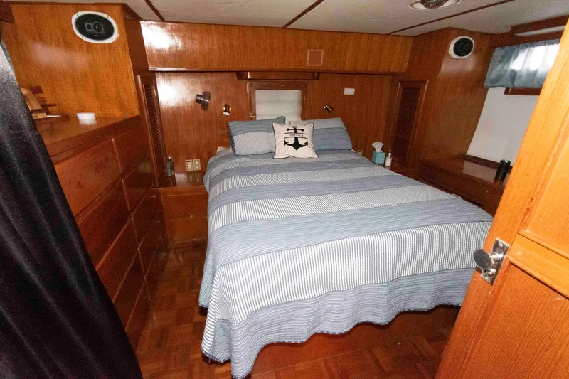 Slide: The Image of 1988 Marine Trader 48 Trawler bedroom with wood paneling and striped bedding. - 19