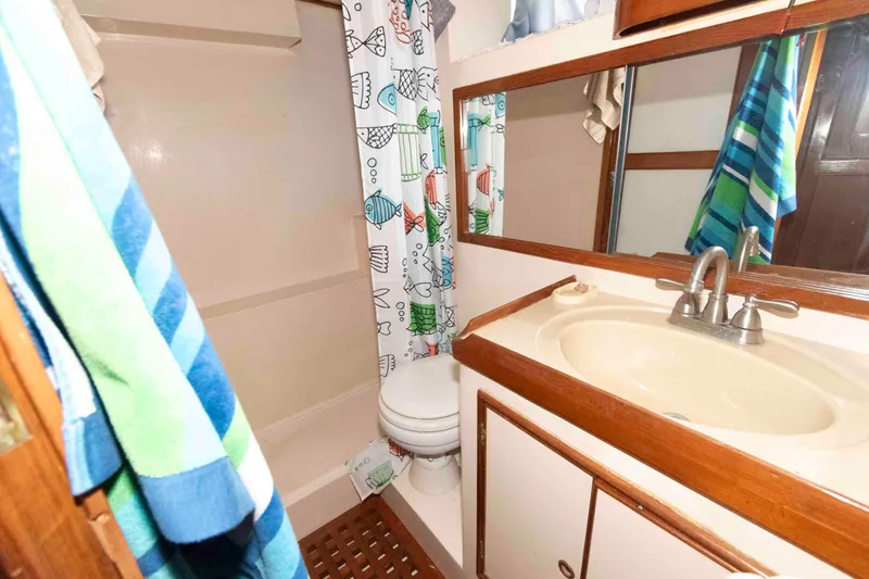 Slide: The Image of 1988 Marine Trader 48 Trawler bathroom with shower, sink, and colorful fish-themed curtain. - 21