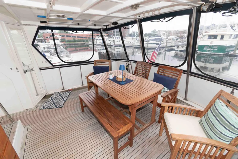Slide: The Image of 1988 Marine Trader 48 Trawler interior with wooden dining set and marina view. - 4