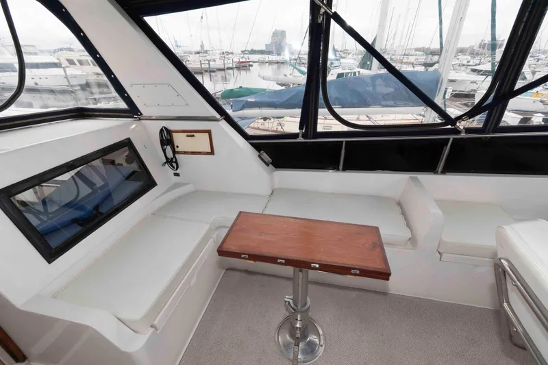 Slide: The Image of 1988 Marine Trader 48 Trawler interior with seating and table, overlooking marina. - 7