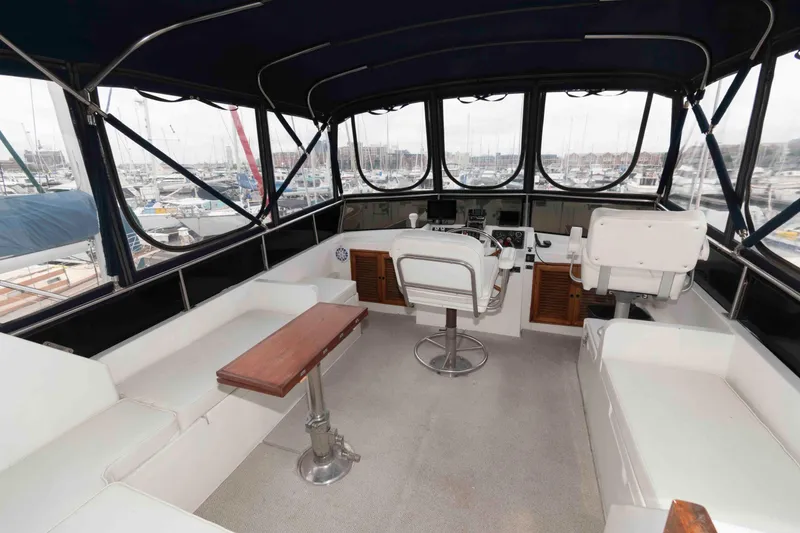 Slide: The Image of 1988 Marine Trader 48 Trawler interior with helm, seating, and marina view. - 8