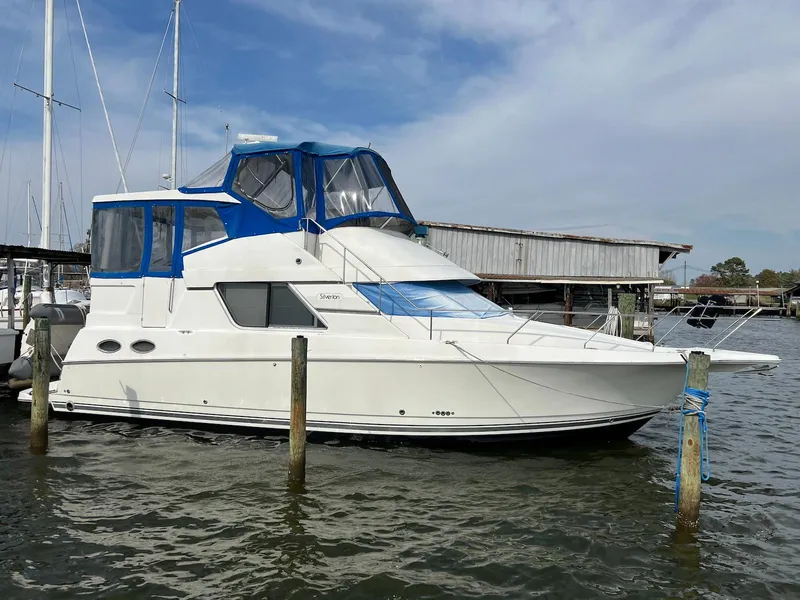 Slide: The Image of 1997 Silverton 372 Motor Yacht docked in marina, featuring blue canopy and sleek design. - 1