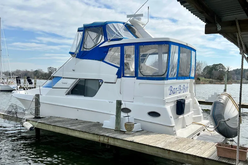 Slide: The Image of 1997 Silverton 372 Motor Yacht docked, featuring blue accents and enclosed cabin. - 2