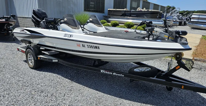 Slide: The Image of 2008 Triton 18X2 boat on trailer, parked outdoors near other boats. - 2