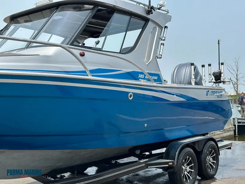 Slide: The Image of 2023 Extreme Boats 745 Game King, blue and silver, on a trailer at a marina. - 8