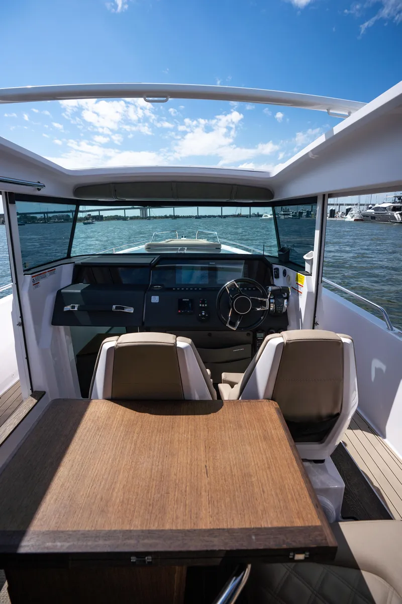 Slide: The Image of 2022 Axopar XC Aft Cabin interior with steering wheel, table, and chairs on a sunny day. - 16