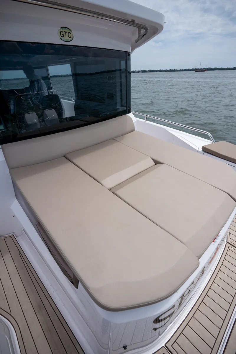 Slide: The Image of 2022 Axopar XC Aft Cabin with spacious sunbed on deck, overlooking calm waters. - 21