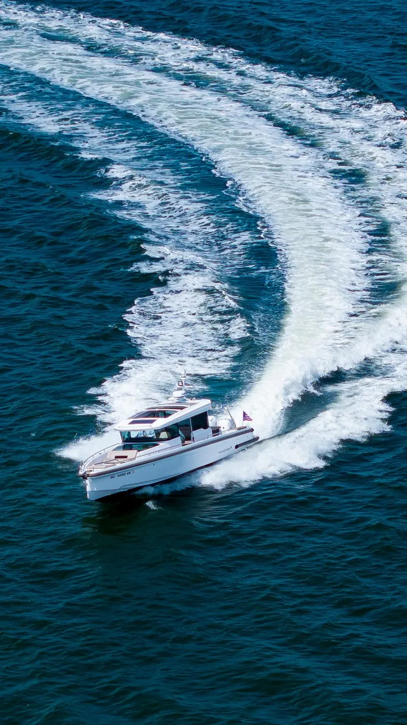 Slide: The Image of 2022 Axopar XC Aft Cabin boat cruising on open water, leaving a wake trail. - 31