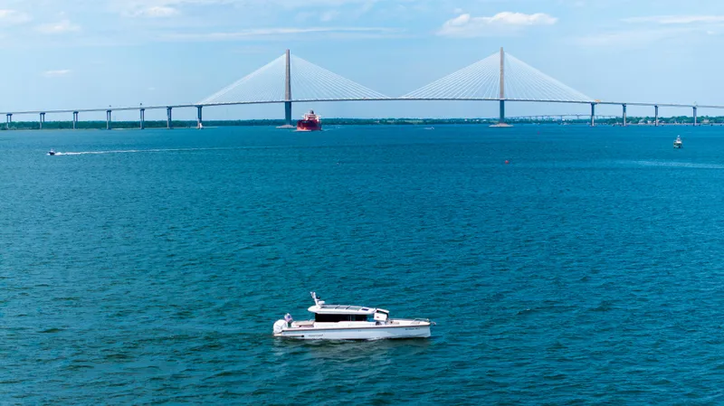 Slide: The Image of 2022 Axopar XC Aft Cabin boat on blue water with a bridge in the background. - 34