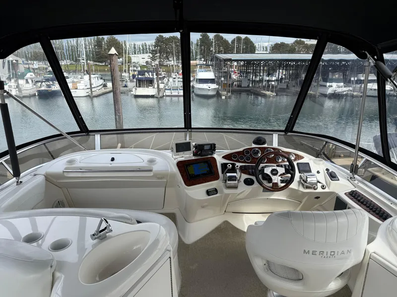 Slide: The Image of 2006 Meridian 391 Sedan yacht helm with marina view, featuring modern controls and seating. - 33