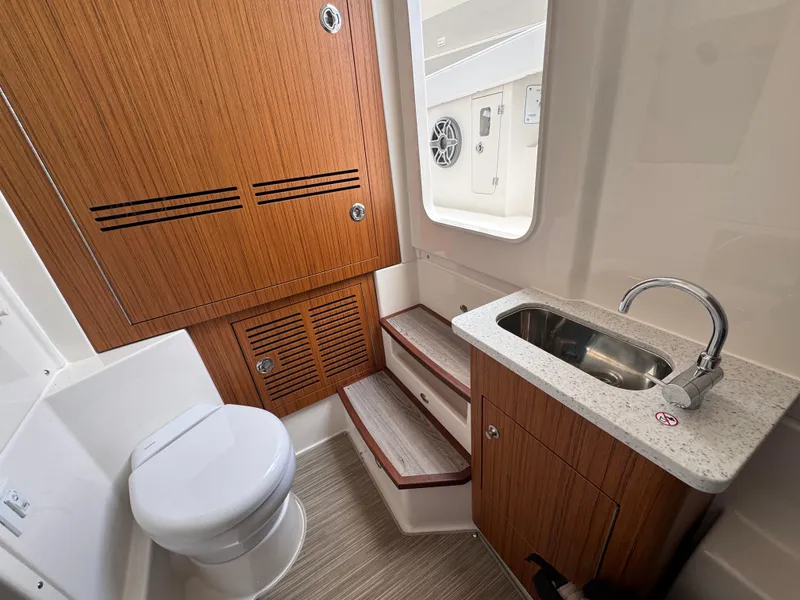 Slide: The Image of 2025 Solace 32 CS boat interior with wooden cabinetry, sink, and toilet. - 23
