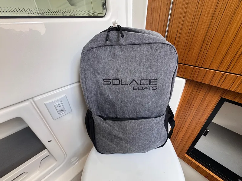 Slide: The Image of Gray Solace Boats backpack inside 2025 Solace 32 CS cabin, featuring sleek wooden paneling. - 28