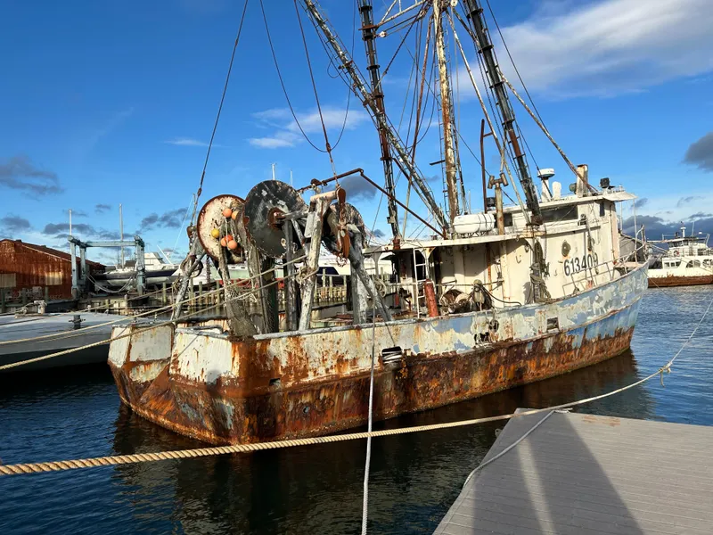 Slide: The Image of Old 1979 Custom Steel Trawler Dragger with rust, docked in a marina under a blue sky. - 4