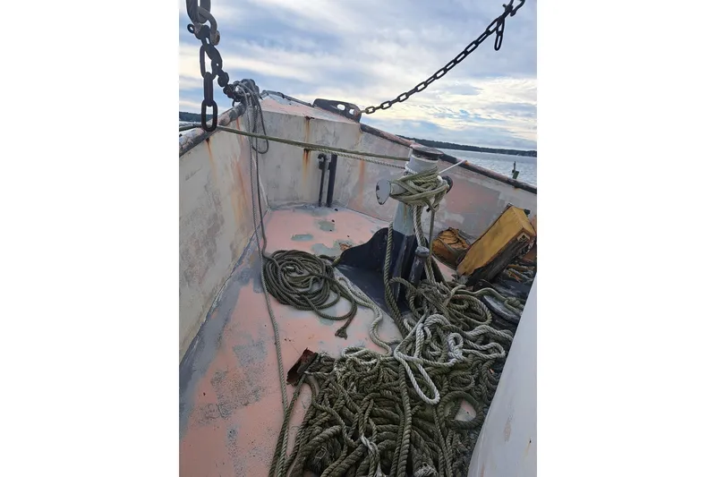 Slide: The Image of Deck of 1979 Custom Steel Trawler Dragger with ropes and chains, under a cloudy sky. - 8