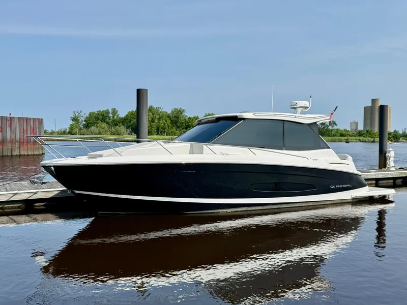 Slide: The Image of 2022 Regal 36 Grande Coupe yacht docked on calm water, clear sky background. - 0