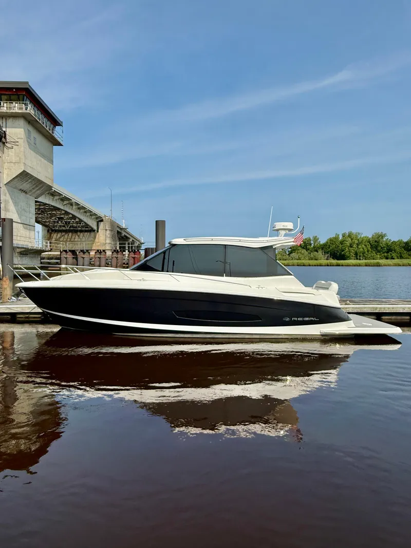 Slide: The Image of 2022 Regal 36 Grande Coupe boat docked by a bridge on a sunny day. - 1