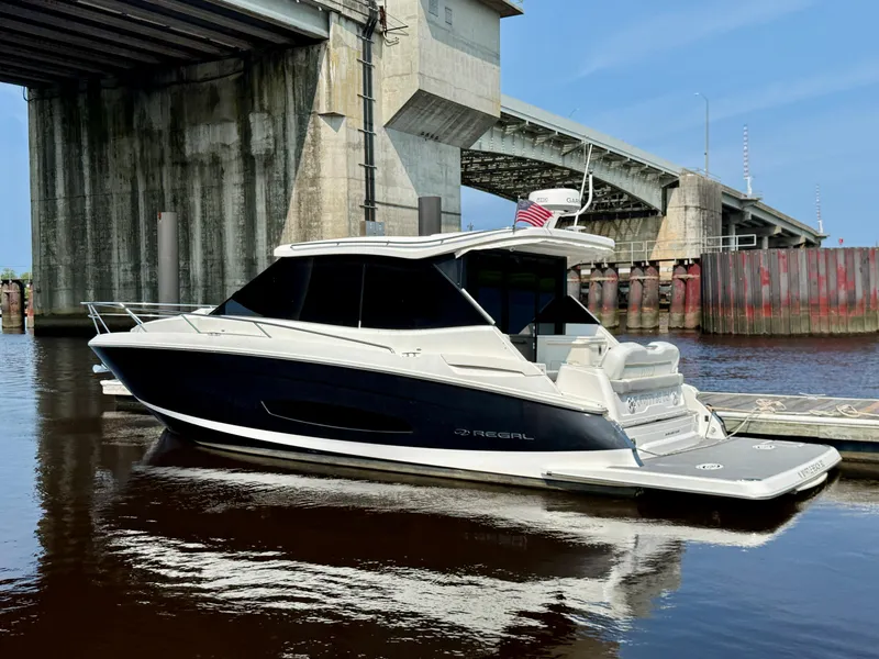 Slide: The Image of 2022 Regal 36 Grande Coupe yacht docked under a bridge on a sunny day. - 2