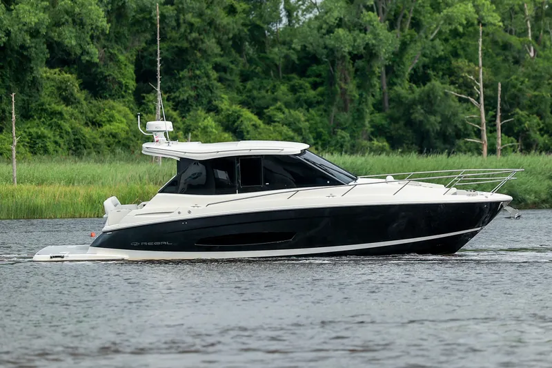 Slide: The Image of 2022 Regal 36 Grande Coupe cruising on a river with lush green background. - 29