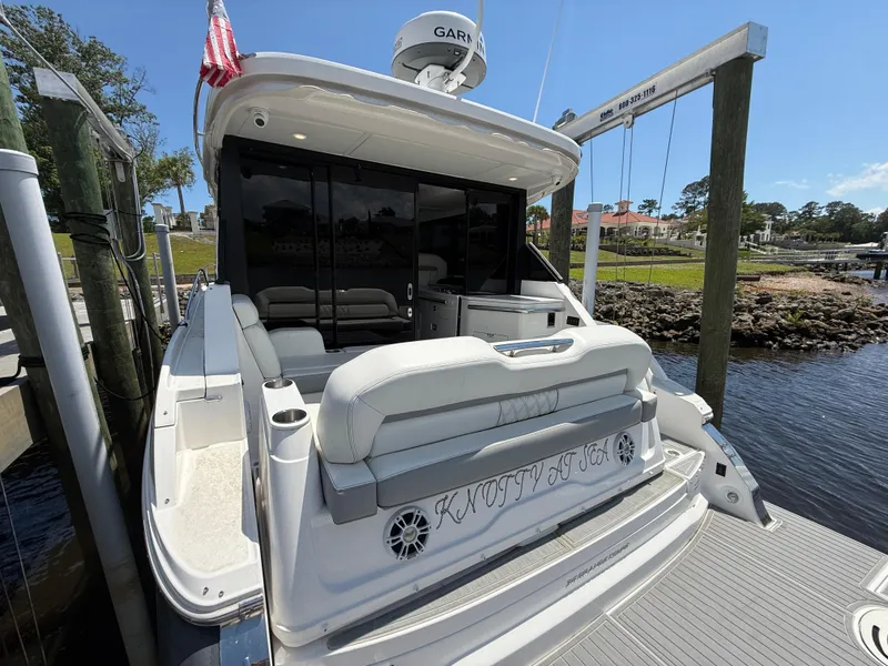 Slide: The Image of 2022 Regal 36 Grande Coupe docked, rear view with seating and American flag. - 5