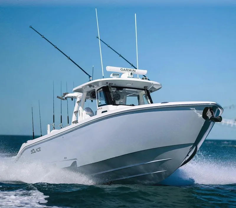 Slide: The Image of 2024 Solace 37 CS boat cruising on open water, equipped with fishing rods and Garmin technology. - 2