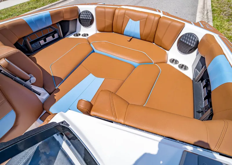 Slide: The Image of 2024 Malibu Wakesetter 24 MXZ interior with brown and blue seating, featuring cup holders and speakers. - 27