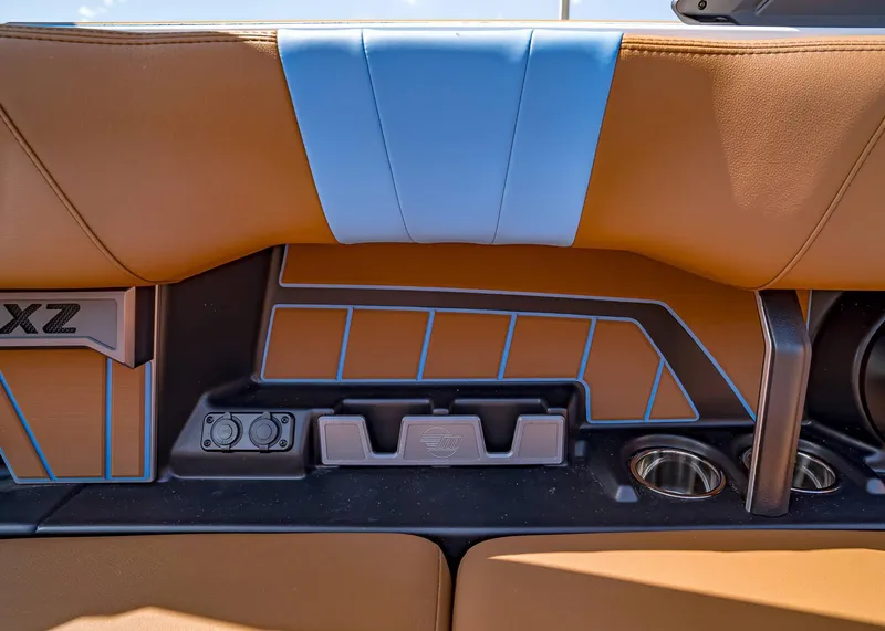 Slide: The Image of 2024 Malibu Wakesetter 24 MXZ interior with tan and blue upholstery, cup holders, and control panel. - 34