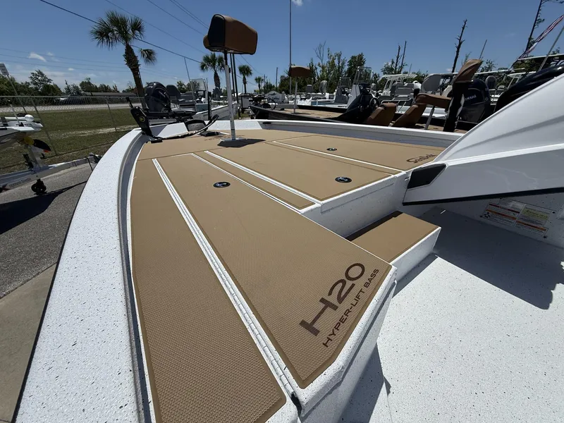 Slide: The Image of 2025 Xpress Hyper-Lift Bass Series boat deck with tan padding and H20 branding. - 2