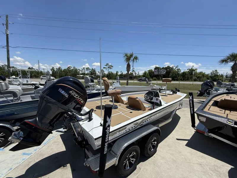 Slide: The Image of 2025 Xpress Hyper-Lift Bass Series boat with Yamaha engine, parked outdoors under clear blue sky. - 6