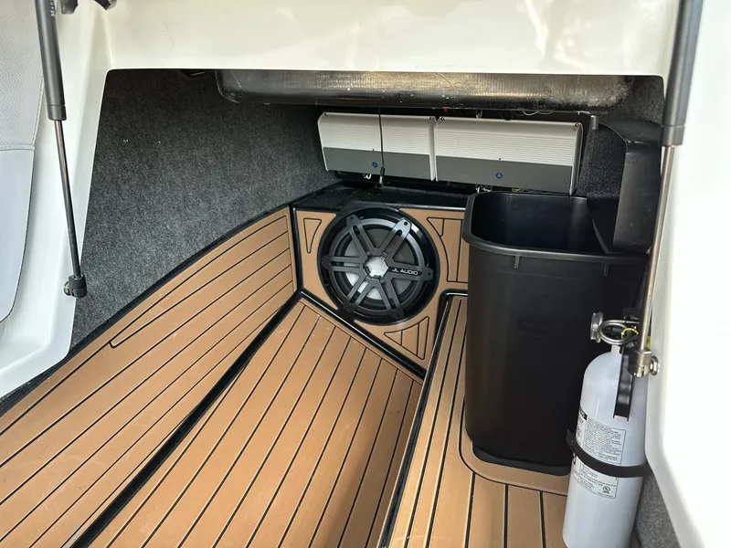 Slide: The Image of 2019 Nautique Super Air Nautique G23 interior with subwoofer, fire extinguisher, and storage bin. - 16