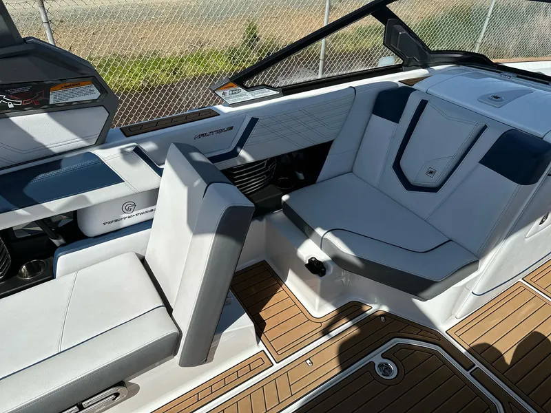 Slide: The Image of 2019 Nautique Super Air Nautique G23 interior with white and gray seating, wooden flooring. - 7