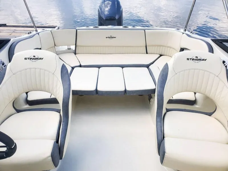 Slide: The Image of 2025 Stingray 211 DC boat interior with white and gray seating, on calm water. - 10