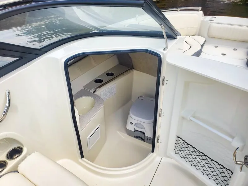 Slide: The Image of 2025 Stingray 211 DC boat interior with compact restroom and seating area. - 12