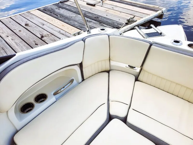 Slide: The Image of 2025 Stingray 211 DC boat interior with cream seating near wooden dock. - 13