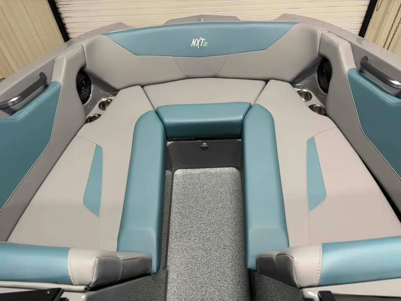 Slide: The Image of 2025 MasterCraft NXT24 boat interior with blue and gray seating, cup holders, and sleek design. - 12