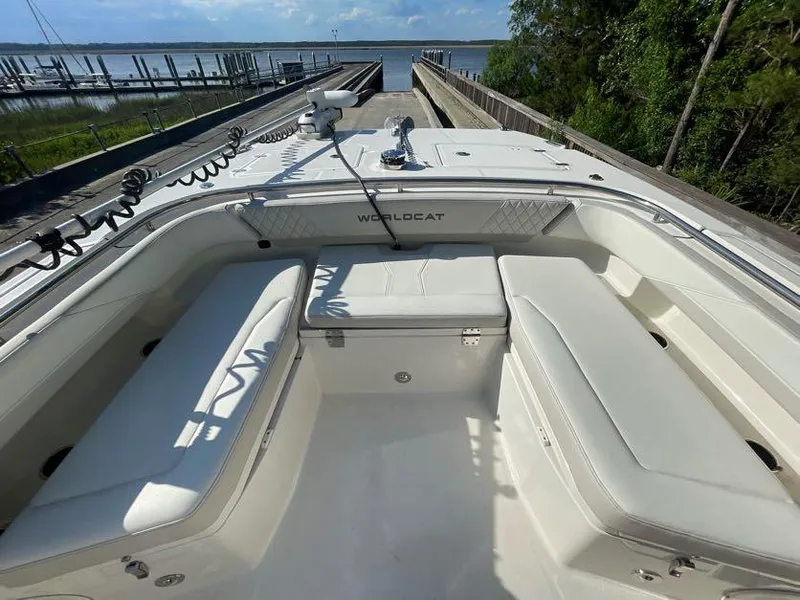 Slide: The Image of 2023 World Cat 260 CC-X boat interior with white seating, docked by a scenic waterfront. - 13