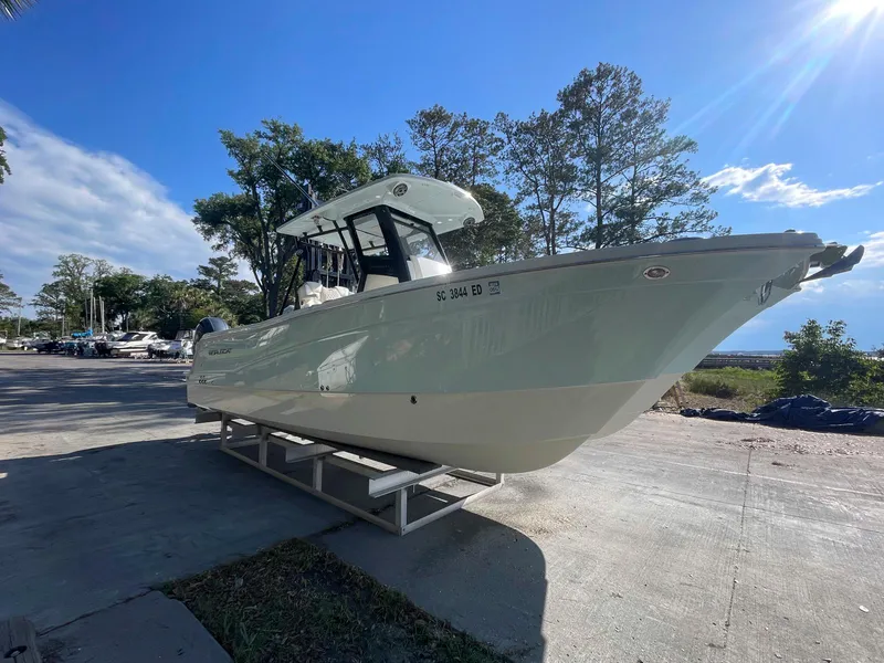 Slide: The Image of 2023 World Cat 260 CC-X boat on a trailer, parked outdoors under a clear blue sky. - 2