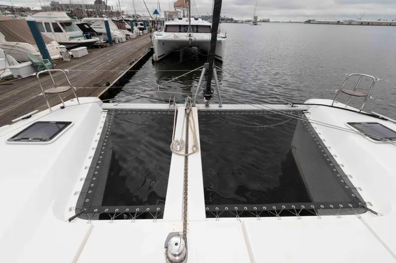 Slide: The Image of 2019 Lagoon 42 catamaran docked at marina, featuring spacious deck and netting. - 19