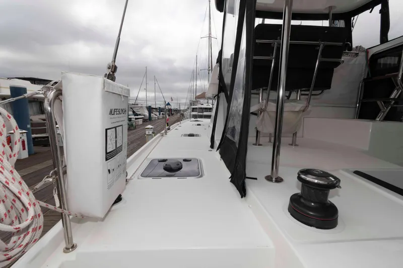 Slide: The Image of 2019 Lagoon 42 yacht deck with winch and equipment, docked at marina under cloudy skies. - 9