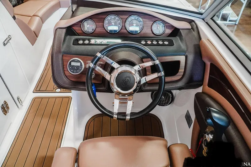 Slide: The Image of Steering wheel and dashboard of a 2013 Cobalt A28 boat, featuring wood accents and gauges. - 18