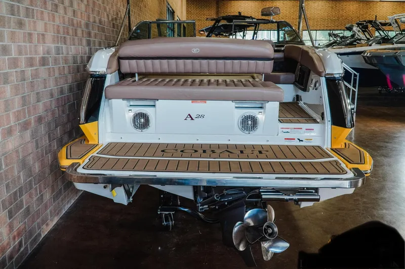 Slide: The Image of 2013 Cobalt A28 boat with teak swim platform and dual speakers in a showroom. - 19