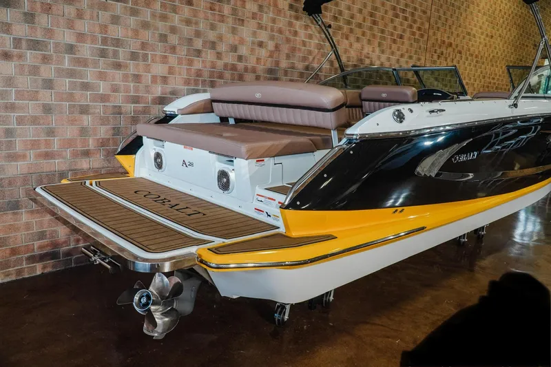 Slide: The Image of 2013 Cobalt A28 boat with yellow accents, displayed indoors against a brick wall. - 3