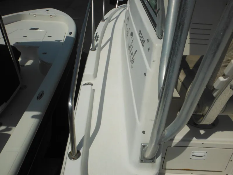 Slide: The Image of 2002 Robalo R235 Walkaround boat deck with railing and adjacent vessel. - 21