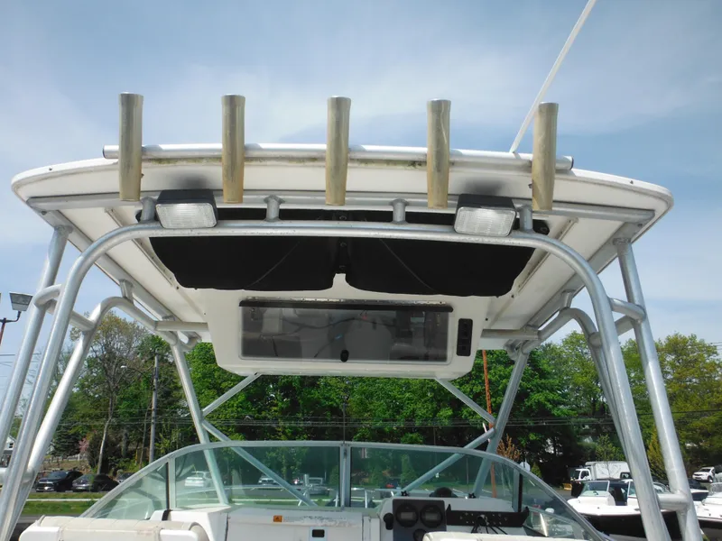 Slide: The Image of 2002 Robalo R235 Walkaround boat with T-top and rod holders, docked outdoors. - 23