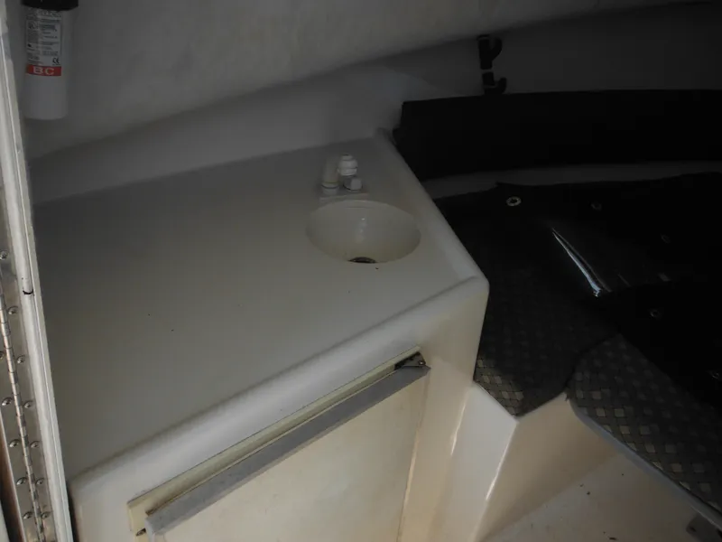 Slide: The Image of 2002 Robalo R235 Walkaround cabin interior with sink and storage area. - 30