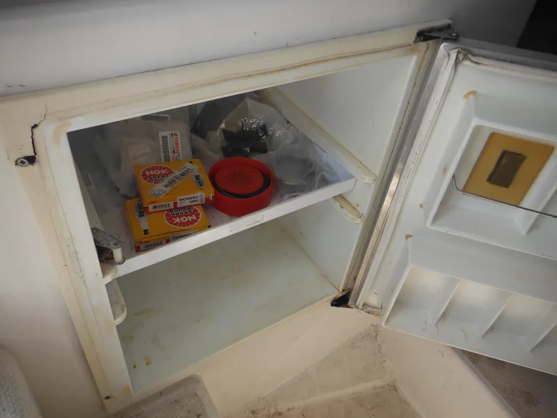 Slide: The Image of Open storage compartment on 2002 Robalo R235 Walkaround boat with various items inside. - 32