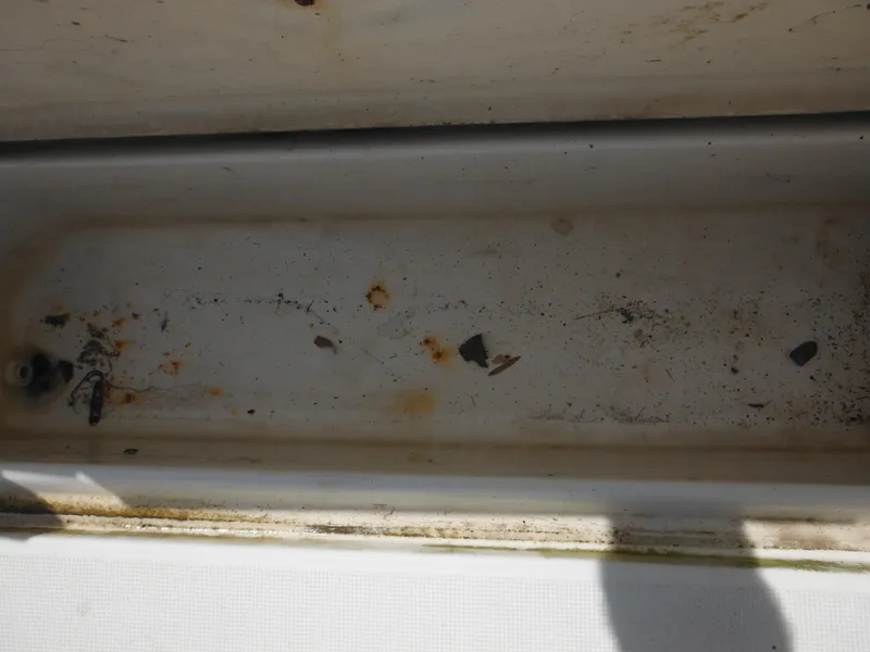 Slide: The Image of Dirty compartment of a 2002 Robalo R235 Walkaround boat, showing rust and debris. - 41