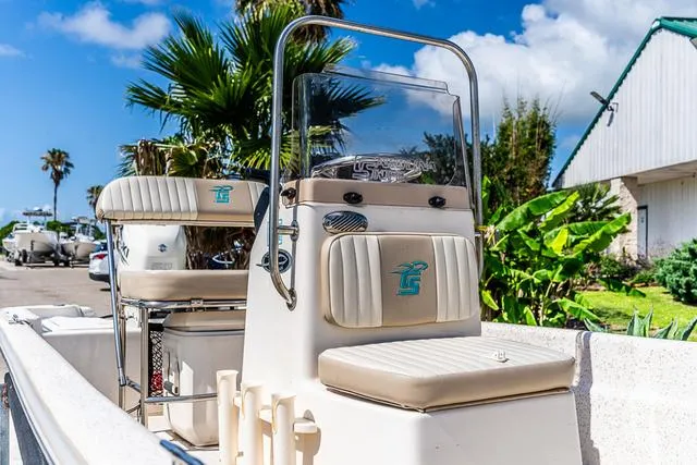 Slide: The Image of 2018 Carolina Skiff 16JVX boat with beige seating, outdoor setting, palm trees, and blue sky. - 6
