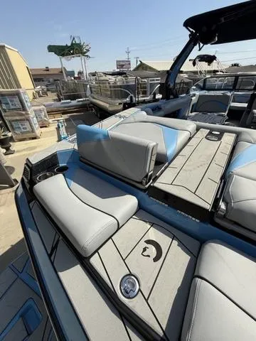 Slide: The Image of 2025 Centurion Fe25 boat interior with gray and blue seating in a marina setting. - 12